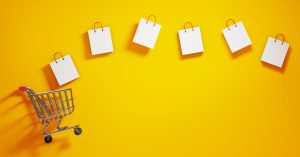 Shopping bags and a shopping cart on yellow background. Horizontal composition with  copy space. Shopping concept.